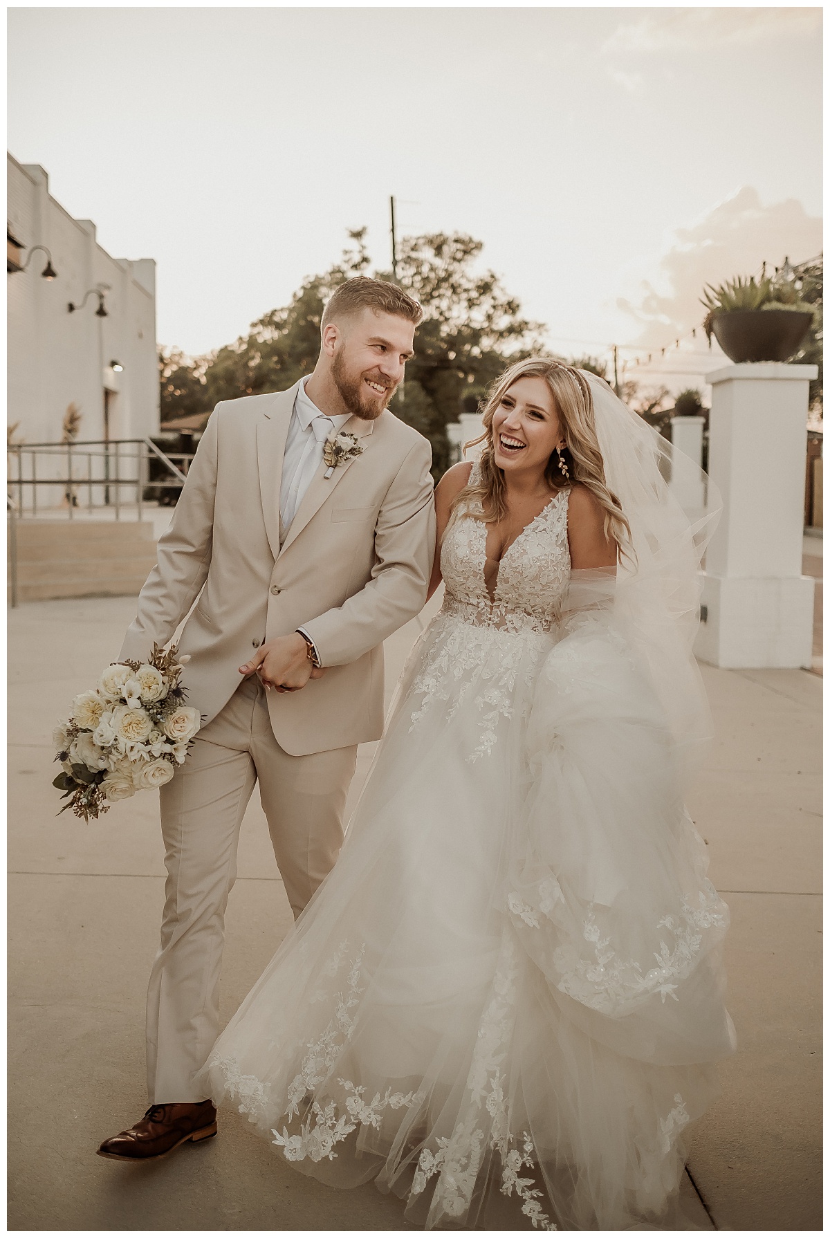 Bride and Groom walking, laughing and holding hands outside of Haus 820 for their industrial boho wedding at Haus 820 captured by Paisley Sunshine Weddings, a Tampa Wedding Photographer.