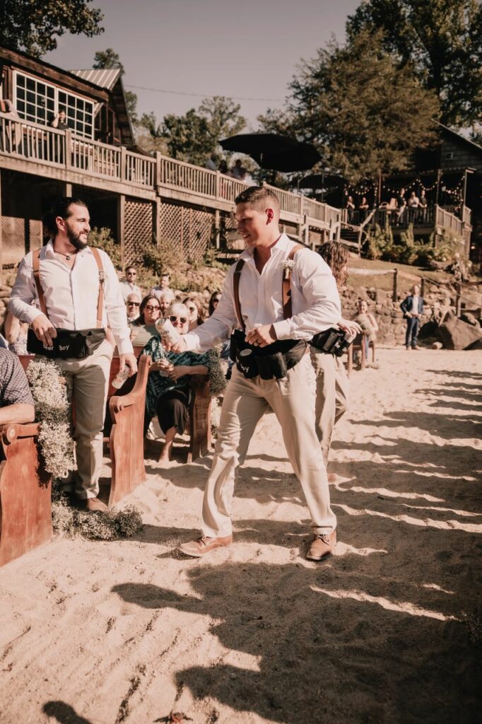Fun twist at the ceremony: Groomsmen passing out beers during the lively riverside celebration at Brown Mountain Beach Resort.