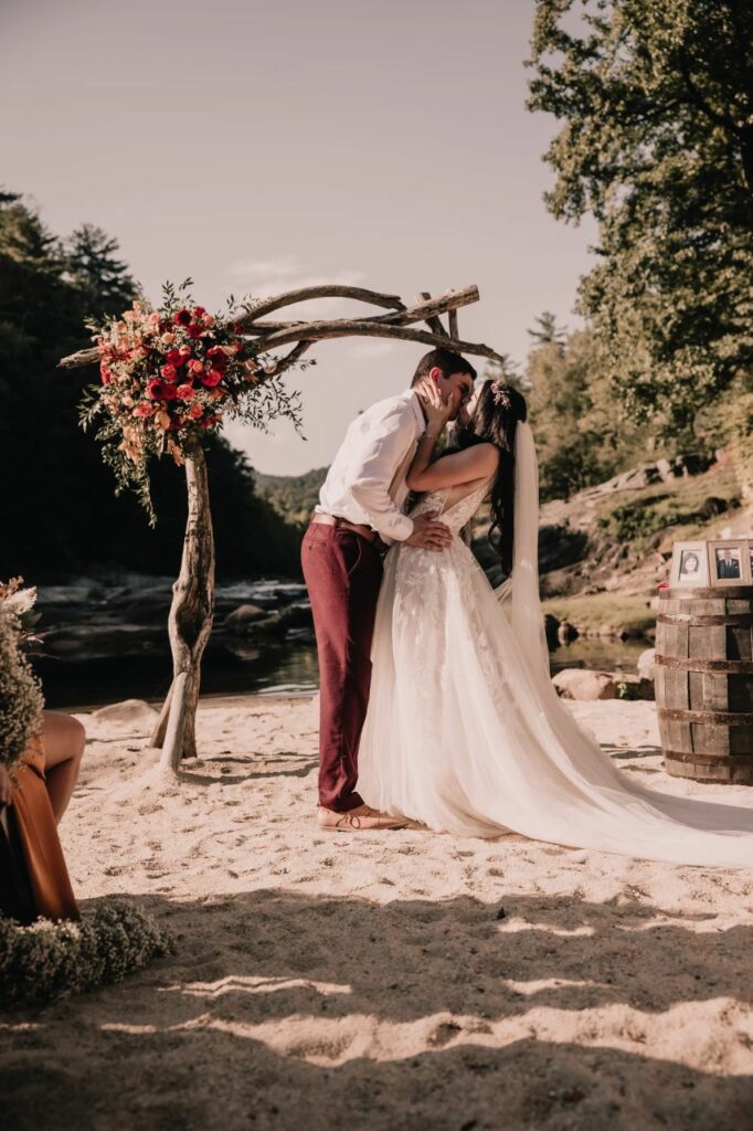 Joyful first kiss as Jonny and Meadow seal their vows in a Christ-centered ceremony by the riverside in North Carolina.
