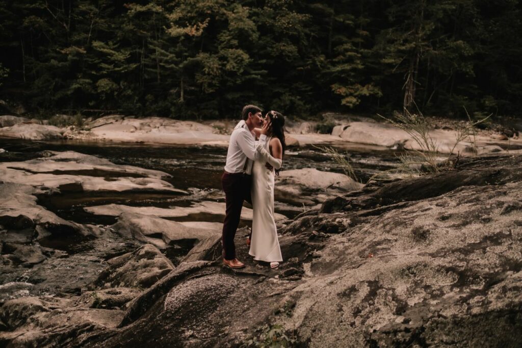 Couple poses against the backdrop of the river and forest at Brown Mountain Beach