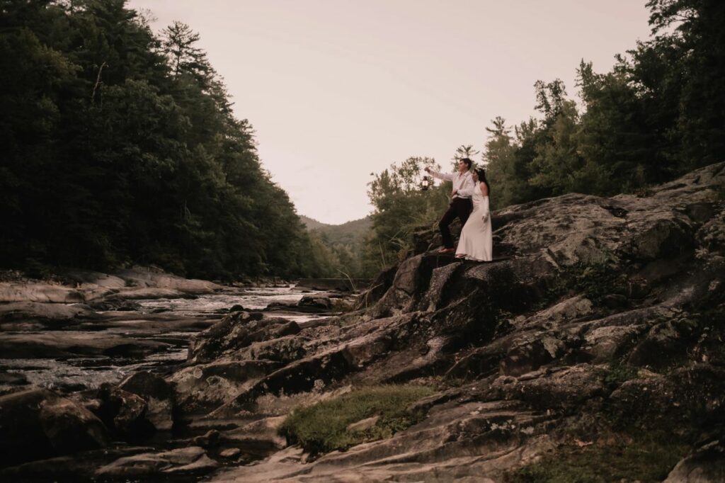 Couple poses against the backdrop of the river and forest at Brown Mountain Beach