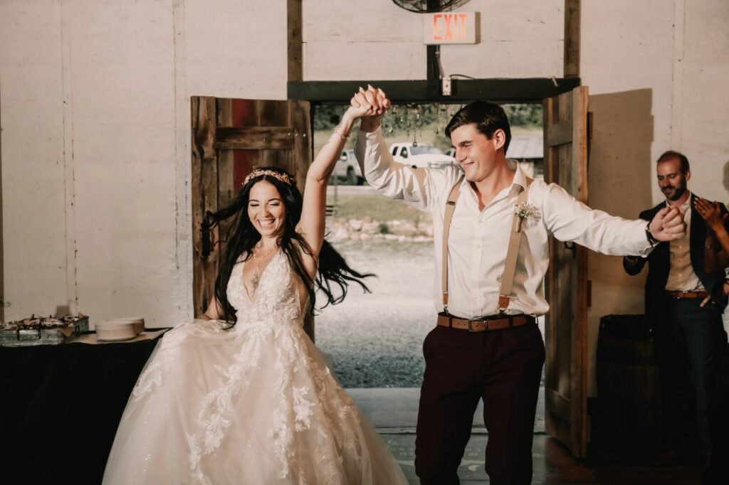 Joyful bride and groom make a grand entrance at their riverside wedding reception.