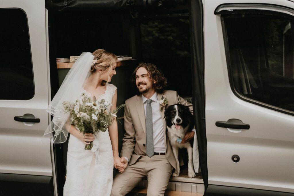 bride and groom posing with their dog and sprinter van