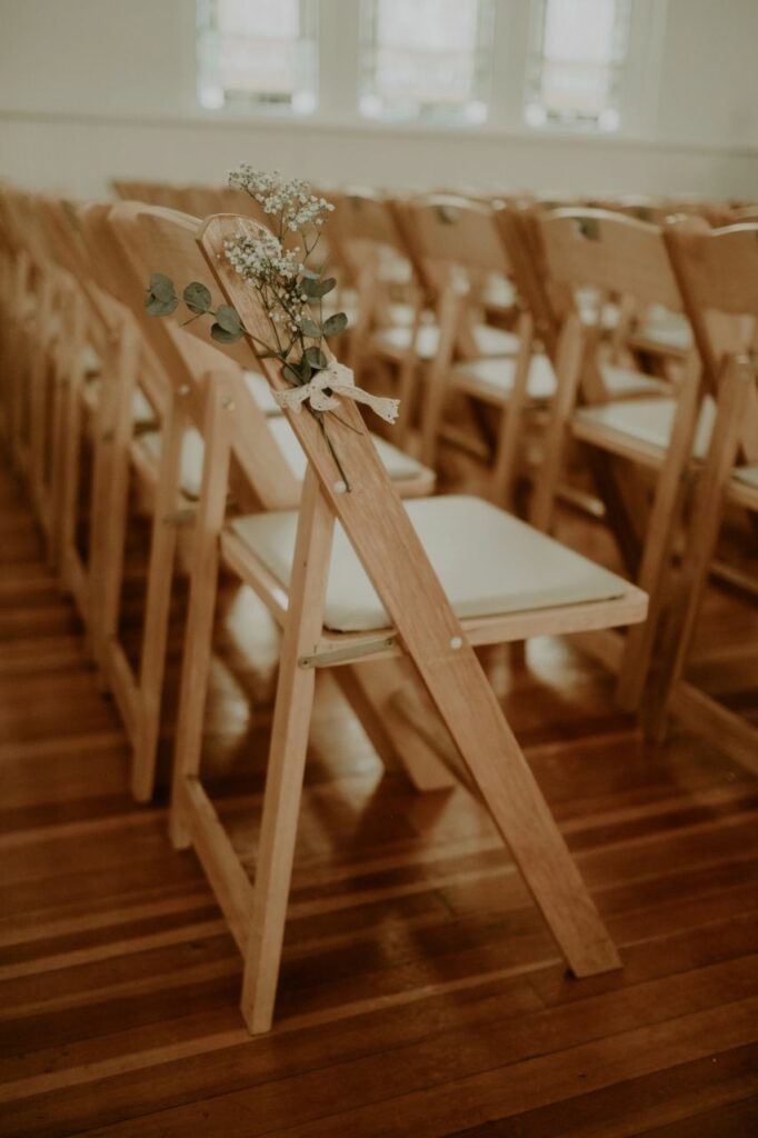 Interior of White Chapel & Harbor Hall in Palm Harbor, FL. Showing chapel chairs decorated with babys breath flowers
