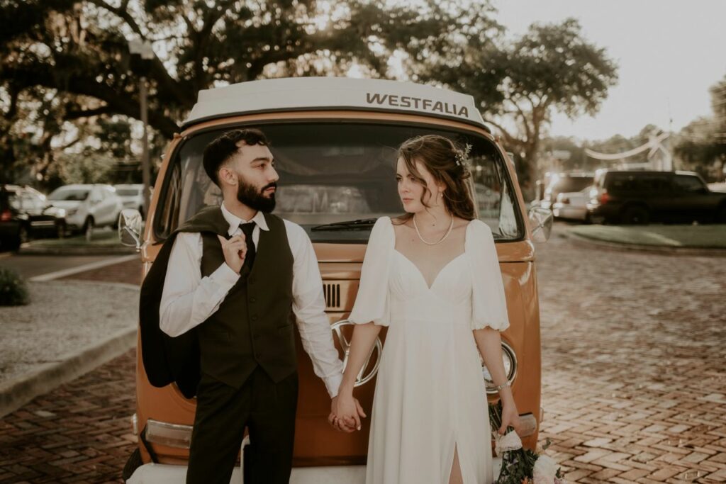 Adorable couple holding hands in front of a vintage Westfalia Volkswagen bus
