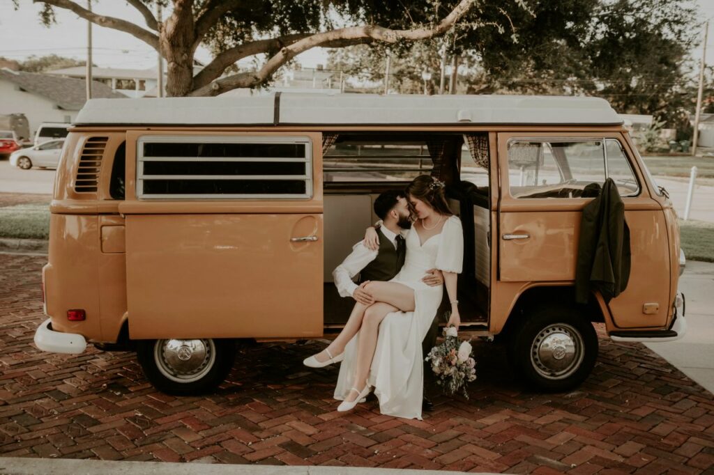 Adorable couple sharing a sweet embrace in front of a vintage Westfalia Volkswagen bus