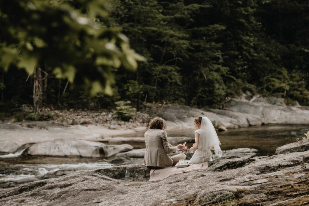bride and groom sitting near the river overlooking the mountains at Brown Mountain Beach Resort