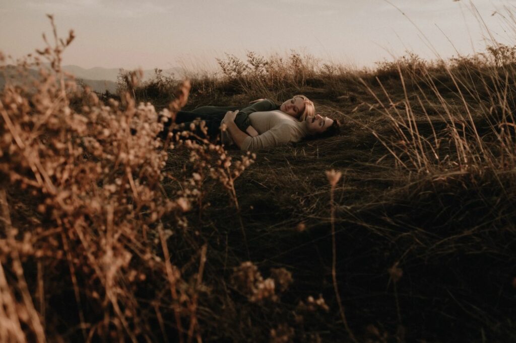 couple laying in the grass at max patch nc for the engagement photos