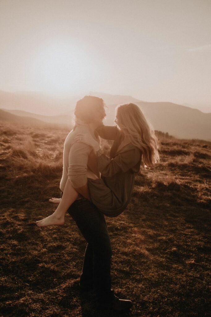 sunset at max patch mountain with a couple embracing for their engagement photos