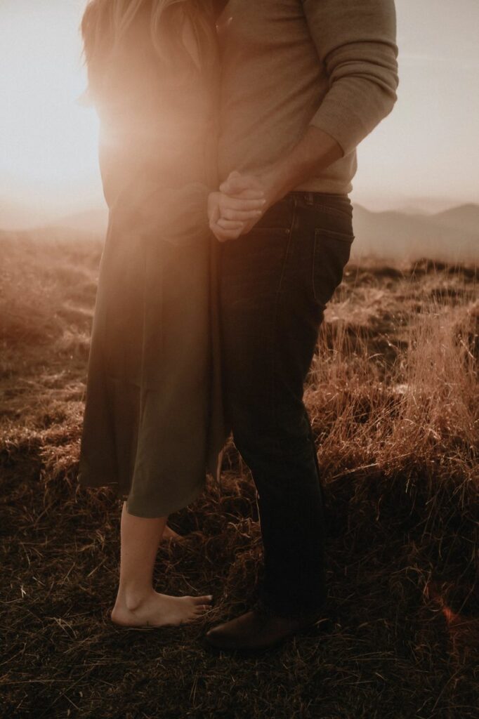 sunset at max patch nc with a couple embracing for the engagement photos