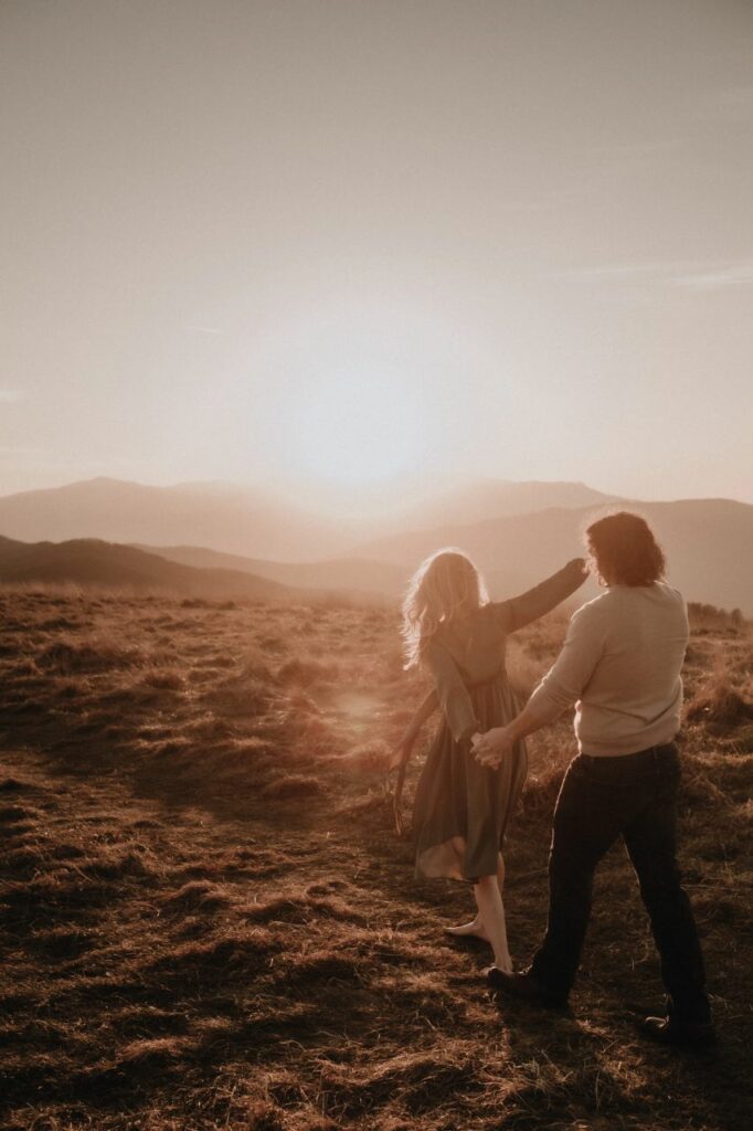 couple dancing at their Max Patch engagement photos with a sunset in the background