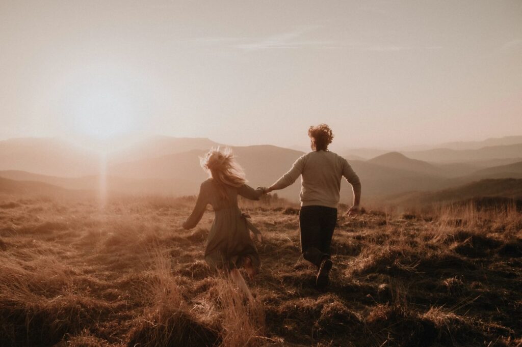 couple holding hands and running in the grassy fields at their Max Patch engagement photos