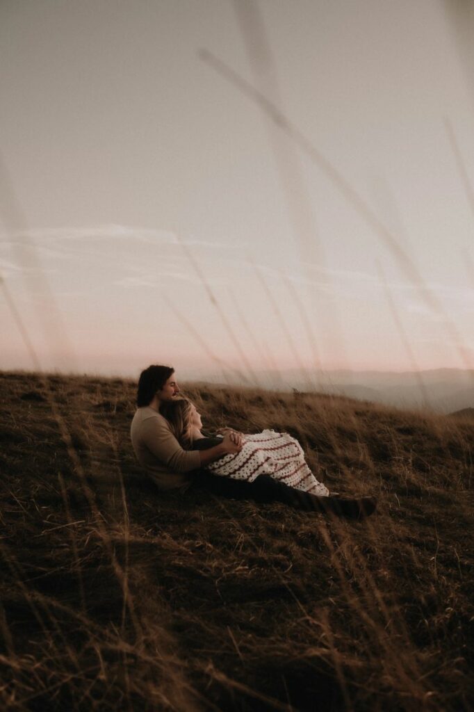 couple cuddled up with a blanket at max patch nc for the engagement photos